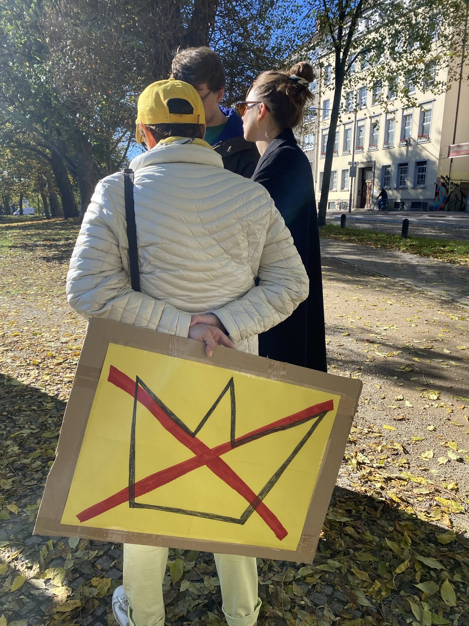 Three protesters displaying a 'No Kings' sign in support of democratic values.